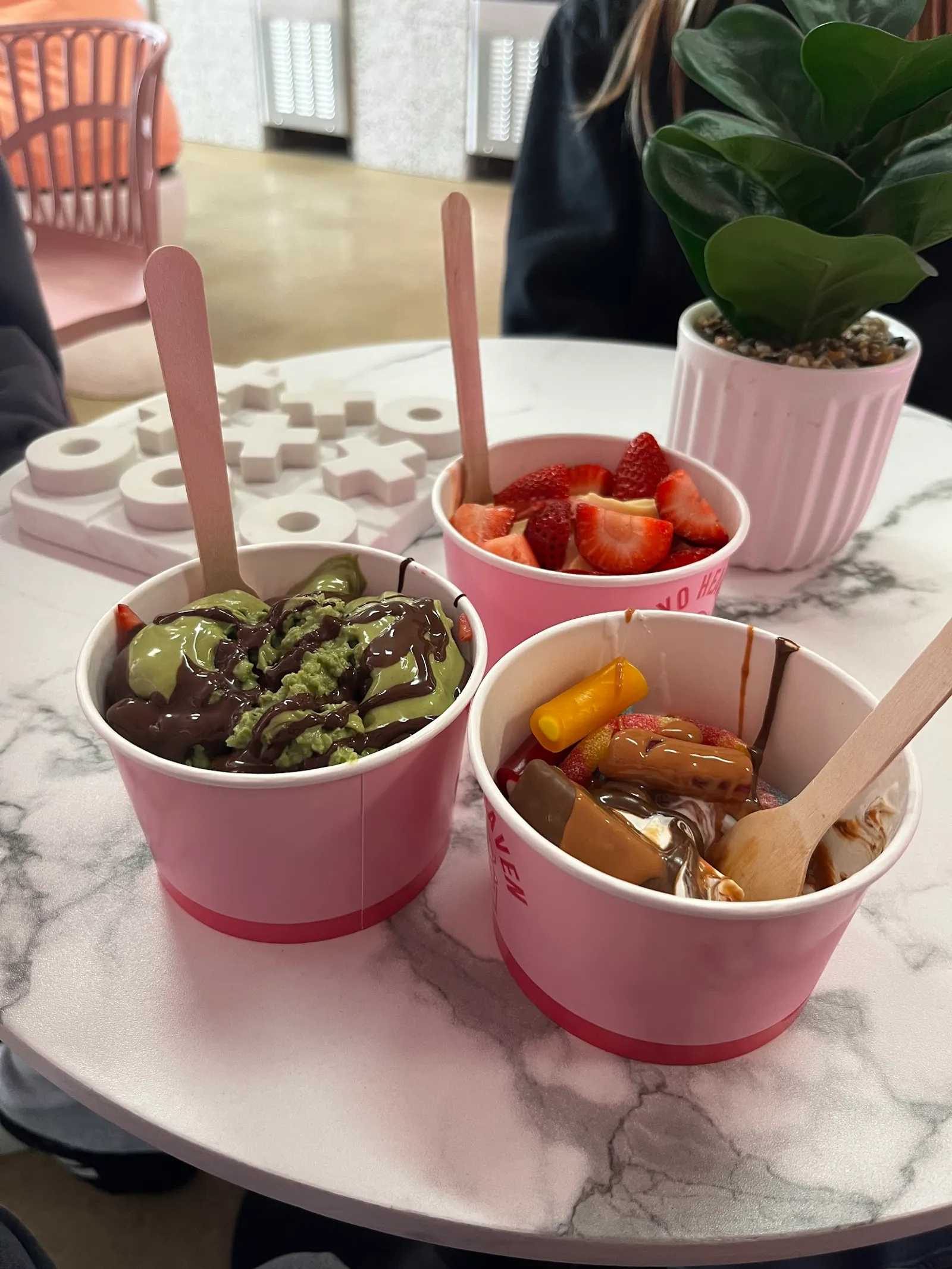 Three Froyo Heaven cups on marble table showing matcha, strawberry and lolly flavour combinations