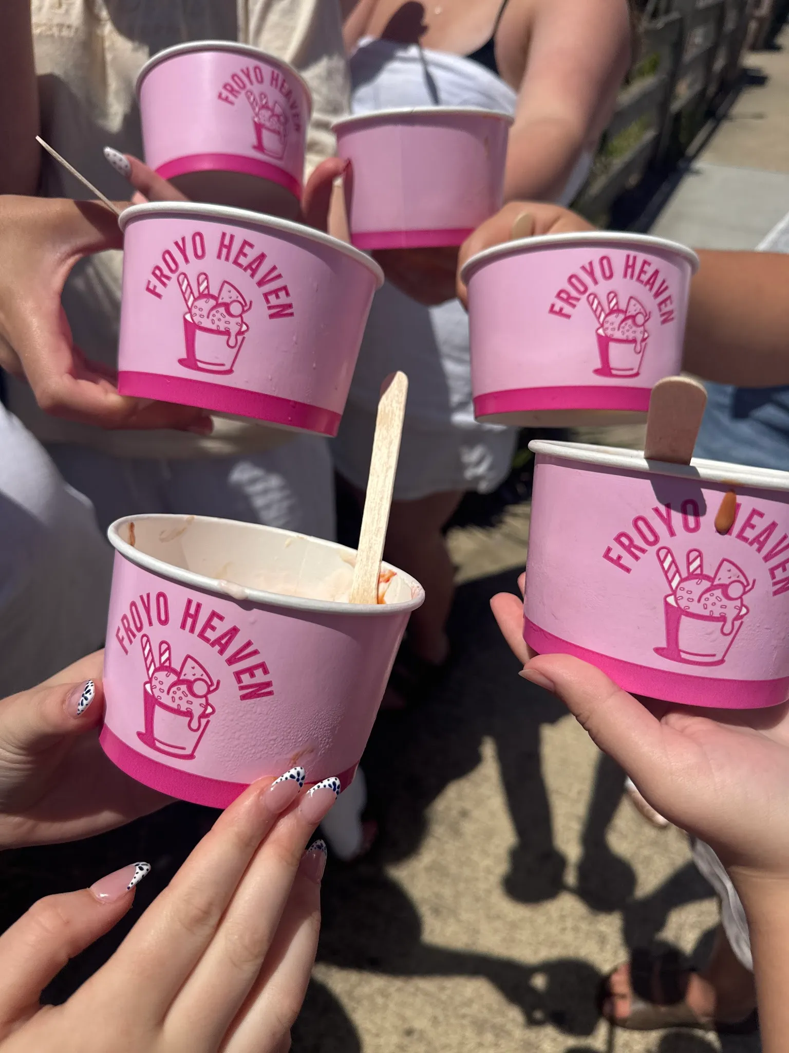 Group toasting with Froyo Heaven branded cups in the sun